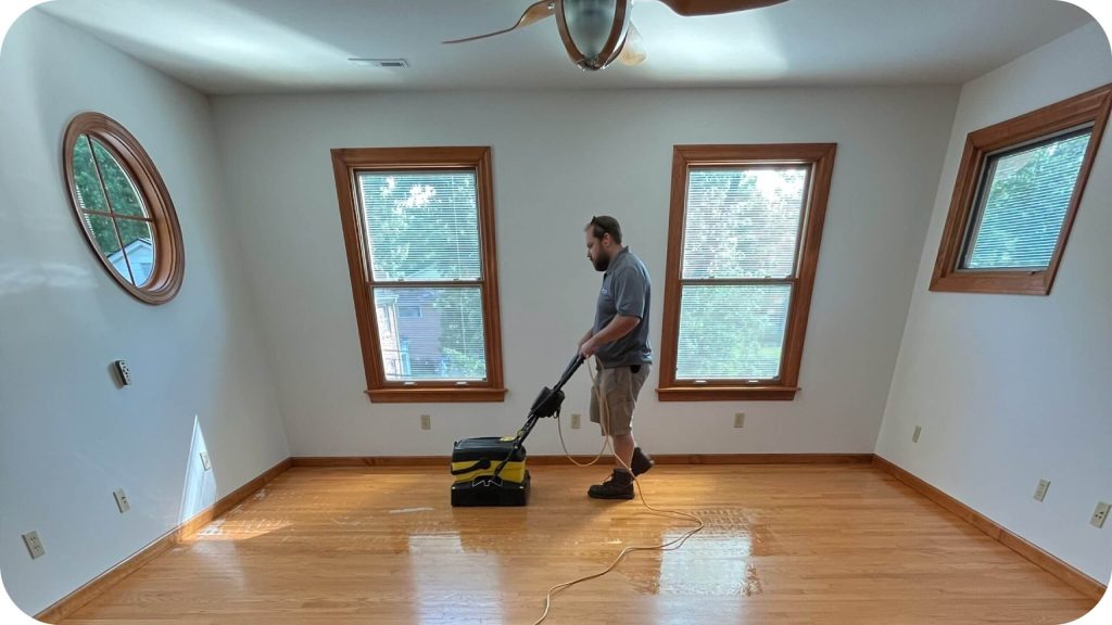A ReCoat Revolution technician removing acrylic and wax contaminants from a hardwood floor.