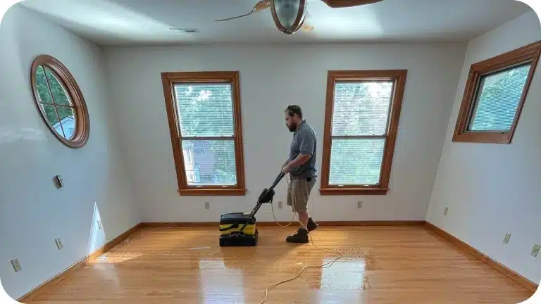 A ReCoat Revolution technician removing acrylic wax and contaminants from a residential hardwood floor to prepare for refinishing.