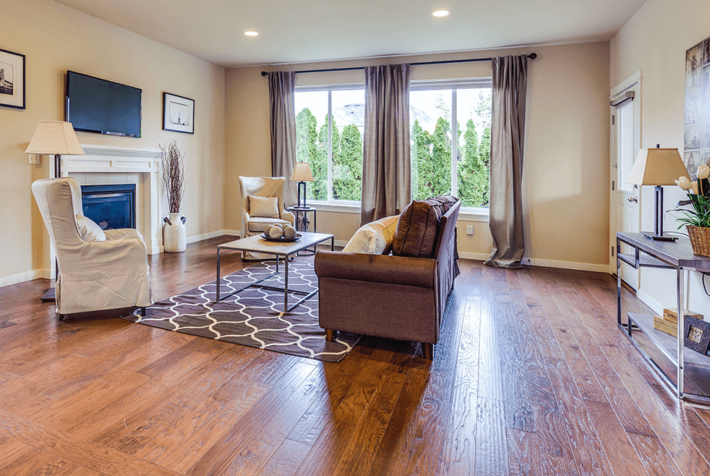 A residential living room with wide plank wood flooring after being refinished by ReCoat Revolution.