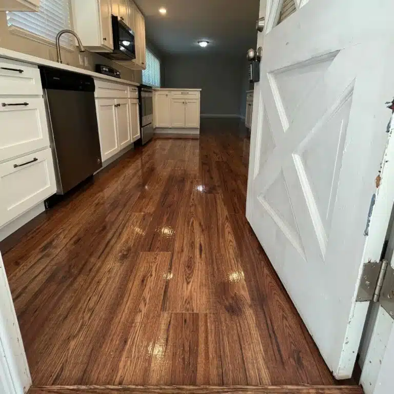 Looking in to a home from an external door of a small kitchen with a newly refinished floor completed by ReCoat Revolution.
