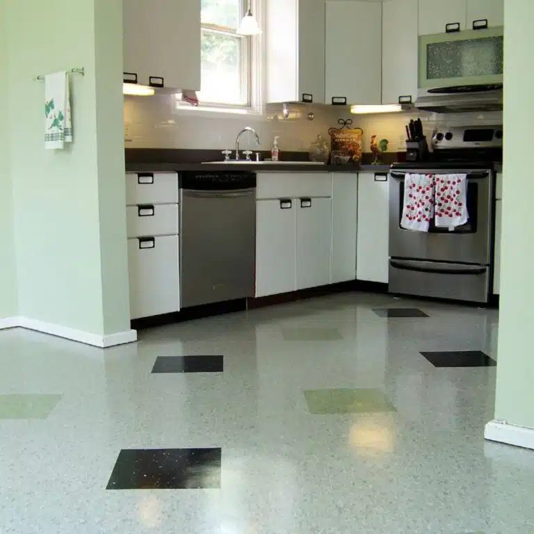 Image of vintage-style square tile floor with alternating gray, black, and green tiles in a vintage-style, residential kitchen with white cabinets, matching green walls, and updated stainless steel appliances.
