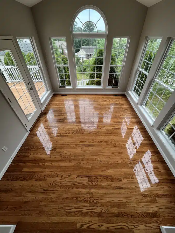 An image from above showcasing the glossy finish of a newly refinished floor by ReCoat Revolution in a bright, residential living room.