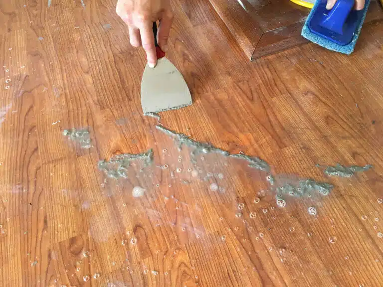 A close-up of the dirty acrylic wax build-up being scraped off after loosened with a solution as performed by ReCoat Revolution.