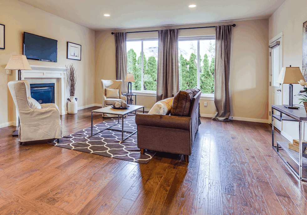A residential living room with wide plank wood flooring after being refinished by ReCoat Revolution.